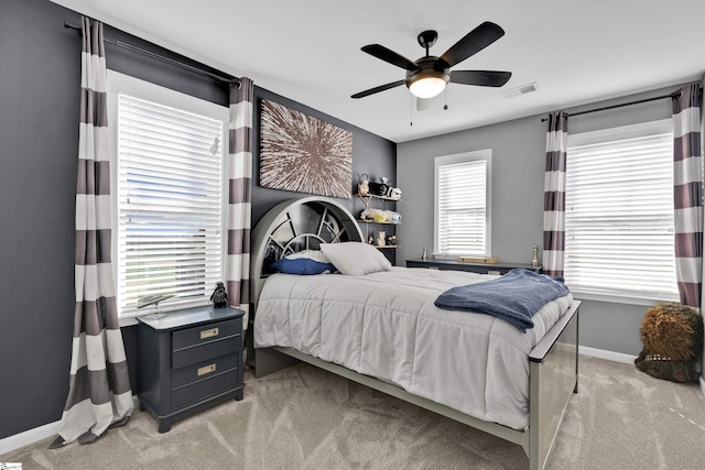 bedroom featuring multiple windows, light colored carpet, and ceiling fan