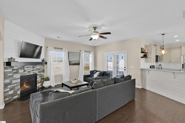 living room featuring a fireplace, ceiling fan, dark hardwood / wood-style flooring, and sink