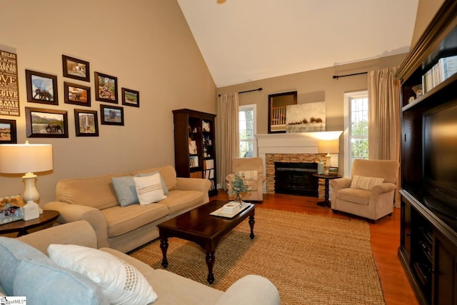 living room featuring a stone fireplace, plenty of natural light, hardwood / wood-style floors, and vaulted ceiling