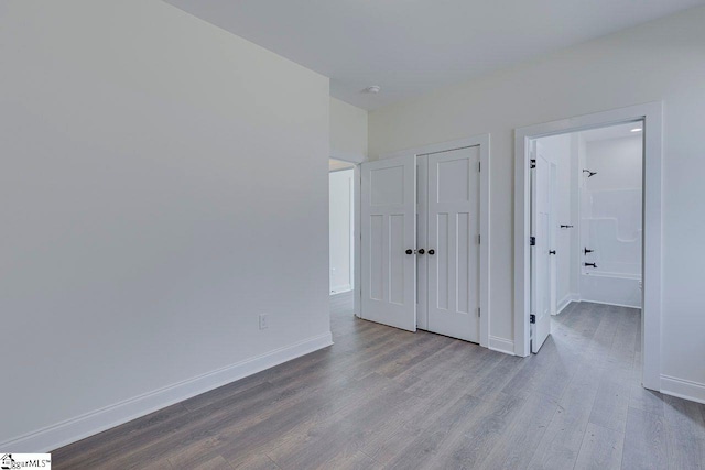 unfurnished bedroom featuring a closet, baseboards, and wood finished floors