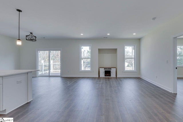 unfurnished living room with dark wood-style floors, a wealth of natural light, and recessed lighting