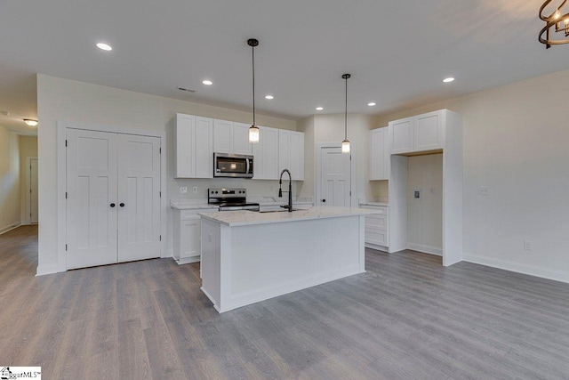 kitchen featuring wood finished floors, appliances with stainless steel finishes, a sink, and white cabinets