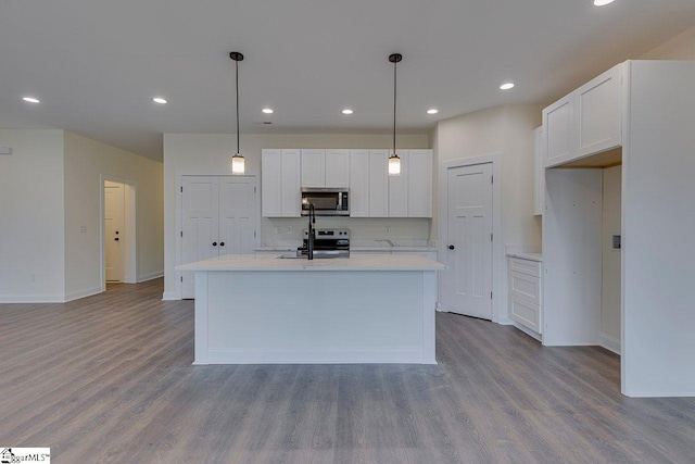 kitchen with appliances with stainless steel finishes, white cabinetry, and wood finished floors