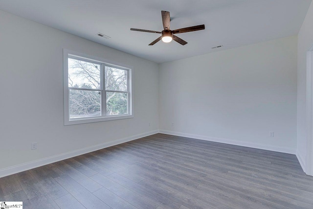 empty room with dark wood-style floors, baseboards, and visible vents