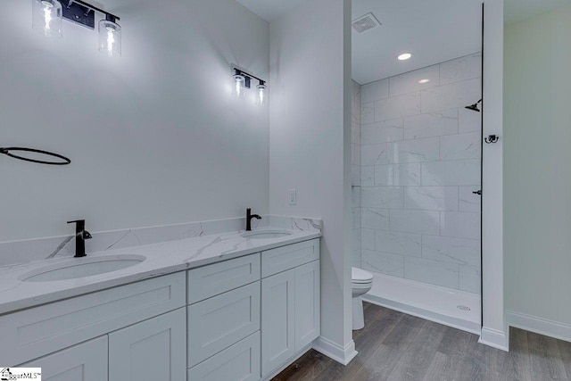 bathroom featuring toilet, visible vents, a sink, and wood finished floors