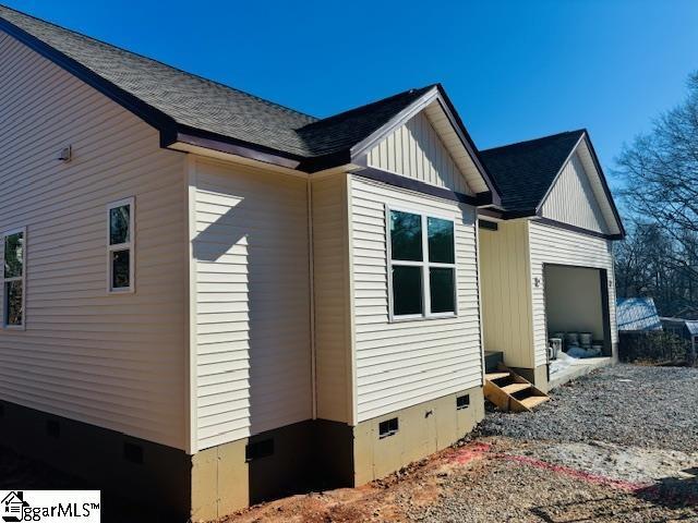 view of side of property featuring crawl space, an attached garage, board and batten siding, and entry steps