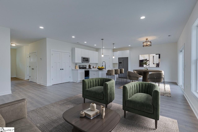 living area with baseboards, wood finished floors, and recessed lighting