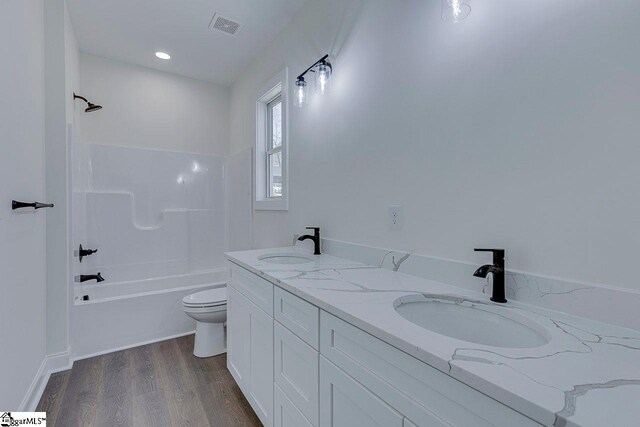 full bathroom with visible vents, a sink, toilet, and wood finished floors