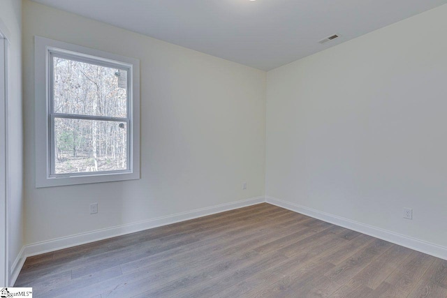 empty room featuring visible vents, baseboards, and wood finished floors