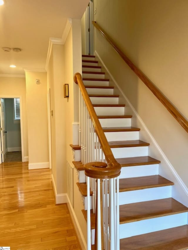 staircase featuring hardwood / wood-style floors and crown molding