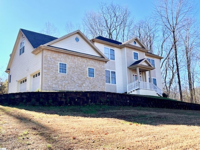 view of side of home with covered porch, a garage, and a lawn