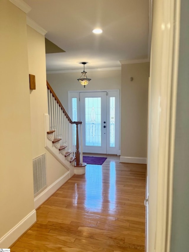 entrance foyer with light hardwood / wood-style flooring and crown molding