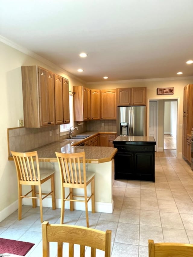 kitchen featuring sink, stainless steel fridge with ice dispenser, backsplash, kitchen peninsula, and a kitchen bar