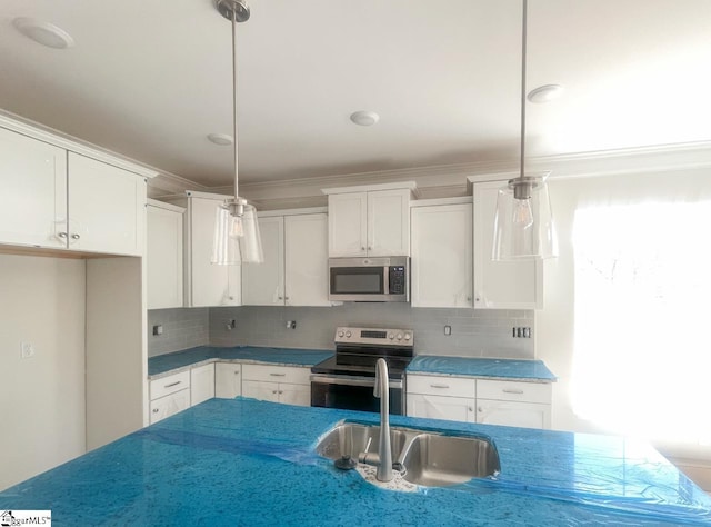 kitchen with a sink, white cabinets, hanging light fixtures, appliances with stainless steel finishes, and tasteful backsplash