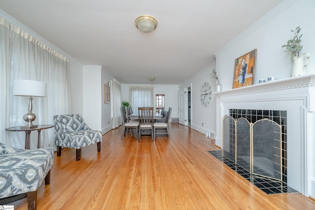 dining room featuring a tiled fireplace, ornamental molding, and hardwood / wood-style flooring