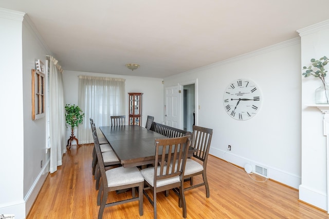 dining space with ornamental molding and light wood-type flooring