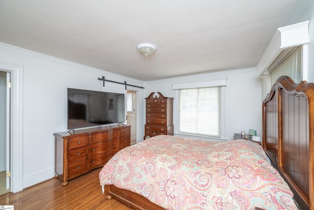 bedroom with a barn door, light wood-type flooring, and ornamental molding