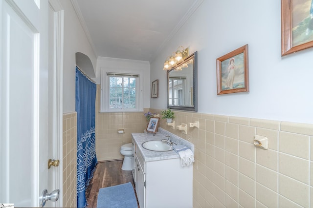 bathroom featuring hardwood / wood-style floors, toilet, vanity, tile walls, and ornamental molding