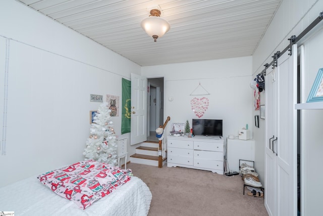 bedroom featuring light carpet and a barn door