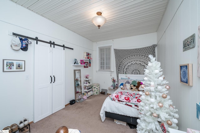 bedroom featuring a barn door and light carpet