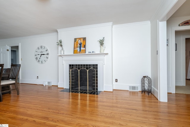 living room featuring crown molding, a fireplace, and light wood-type flooring