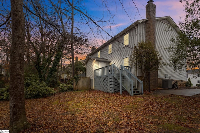 back house at dusk featuring central AC, a patio area, and a wooden deck