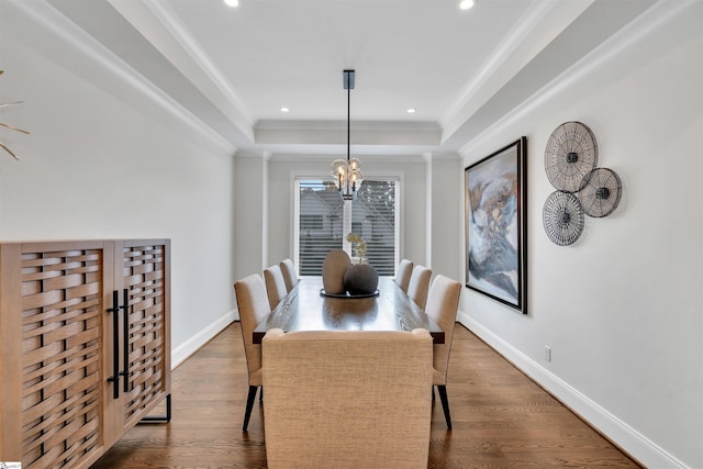 dining area with a tray ceiling, crown molding, dark wood-type flooring, and a notable chandelier