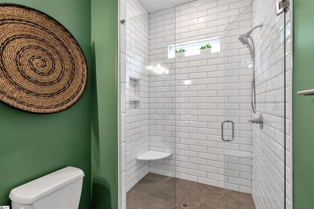 bathroom featuring tile patterned floors, a shower with shower door, and toilet