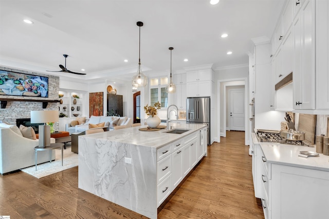 kitchen with white cabinets, pendant lighting, a center island with sink, and sink