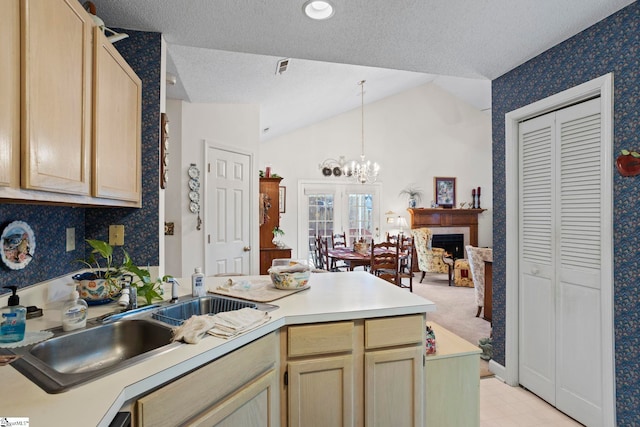 kitchen featuring a textured ceiling, sink, light brown cabinets, pendant lighting, and lofted ceiling