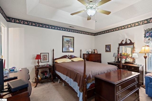 bedroom featuring a raised ceiling, ceiling fan, and light colored carpet