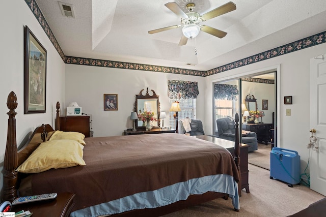 carpeted bedroom with a raised ceiling, ceiling fan, access to exterior, and a textured ceiling