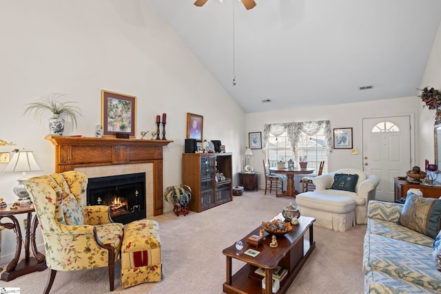 carpeted living room featuring a tile fireplace, ceiling fan, and high vaulted ceiling