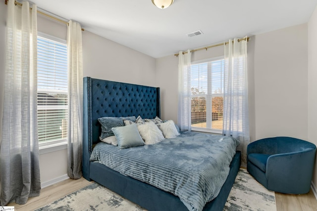 bedroom with light hardwood / wood-style floors and multiple windows