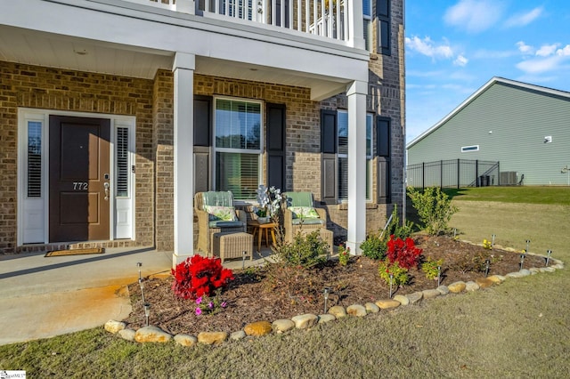 view of exterior entry with a balcony and a lawn