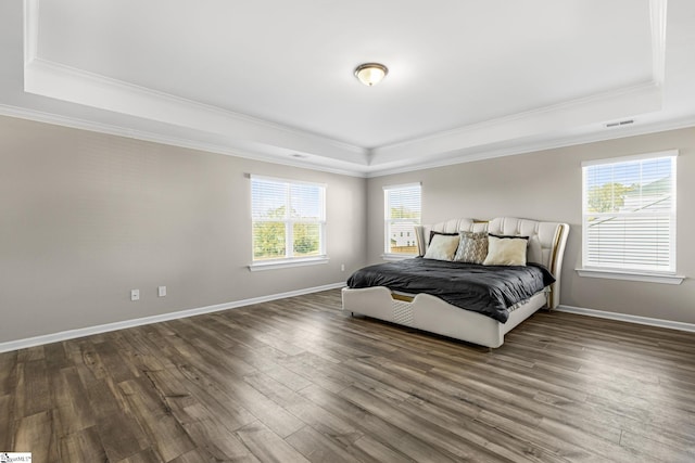 bedroom with a raised ceiling, multiple windows, dark wood-type flooring, and ornamental molding