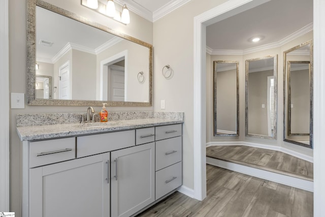 bathroom with wood-type flooring, vanity, and ornamental molding