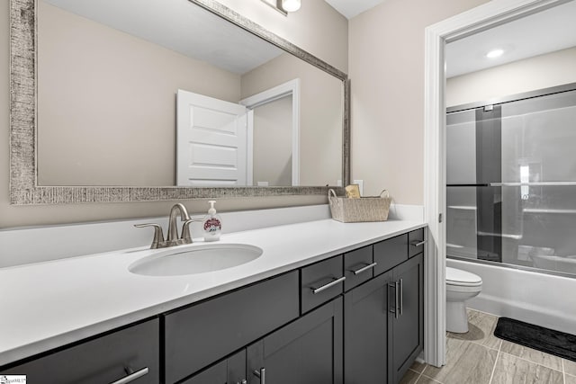 full bathroom featuring combined bath / shower with glass door, vanity, and toilet