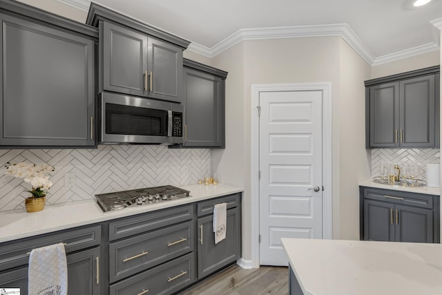 kitchen featuring appliances with stainless steel finishes, backsplash, light hardwood / wood-style floors, and gray cabinetry