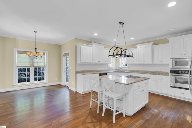 kitchen featuring a center island, sink, stainless steel appliances, pendant lighting, and white cabinets