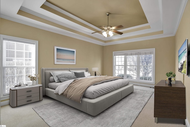 bedroom featuring ceiling fan, light colored carpet, crown molding, and a tray ceiling