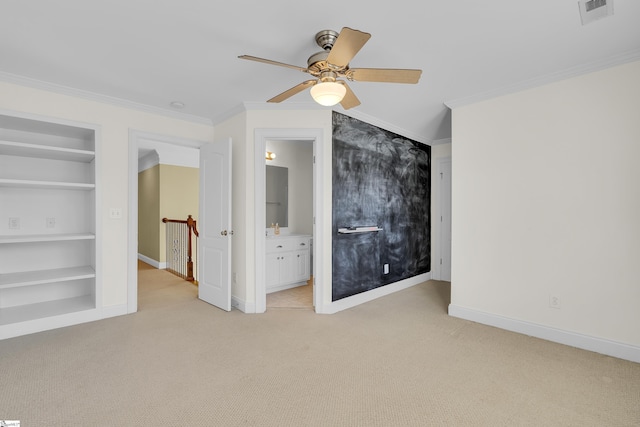 unfurnished bedroom featuring ceiling fan, ensuite bathroom, crown molding, and light carpet