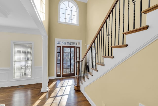 entrance foyer featuring decorative columns, dark hardwood / wood-style flooring, and ornamental molding