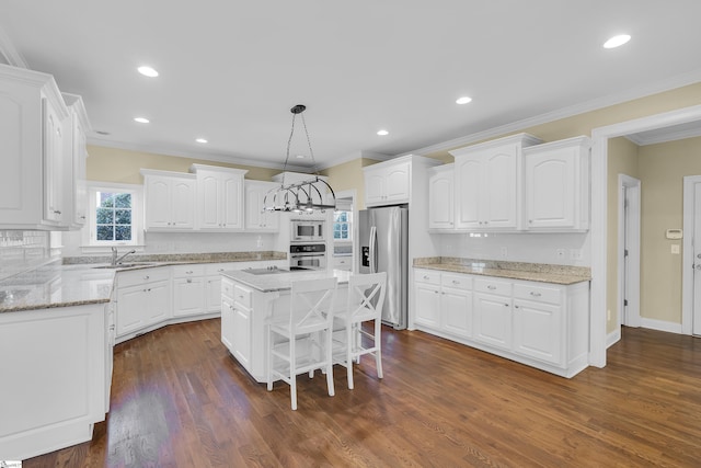 kitchen with white cabinets, a kitchen island, hanging light fixtures, and appliances with stainless steel finishes