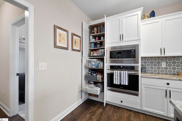 kitchen featuring tasteful backsplash, white cabinetry, stainless steel appliances, and light stone counters