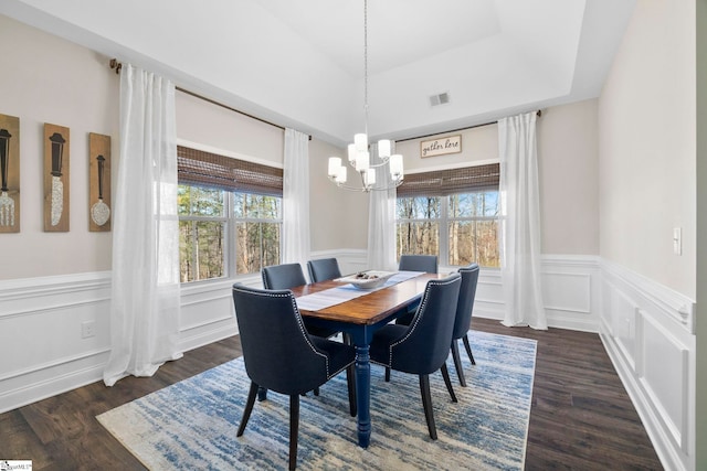 dining area featuring dark hardwood / wood-style floors, a tray ceiling, and a notable chandelier