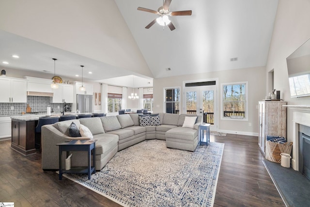 living room with dark hardwood / wood-style flooring, ceiling fan with notable chandelier, high vaulted ceiling, and a wealth of natural light