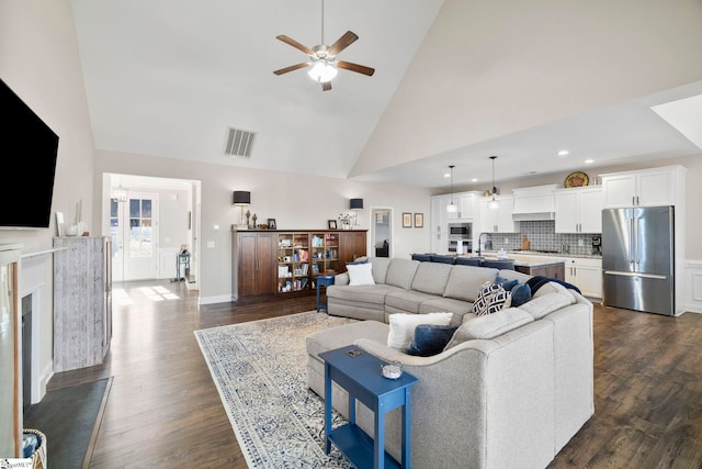 living room featuring dark hardwood / wood-style flooring, high vaulted ceiling, ceiling fan, and sink