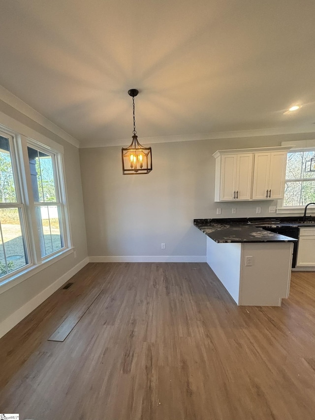 kitchen with white cabinets, pendant lighting, light hardwood / wood-style flooring, and a notable chandelier