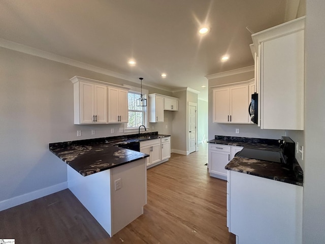 kitchen with white cabinets, pendant lighting, and black / electric stove